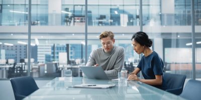 Multiethnic Diverse Office Conference Room Meeting: Team of Two Multiethnic Diverse Evernex employees work together in Meeting room